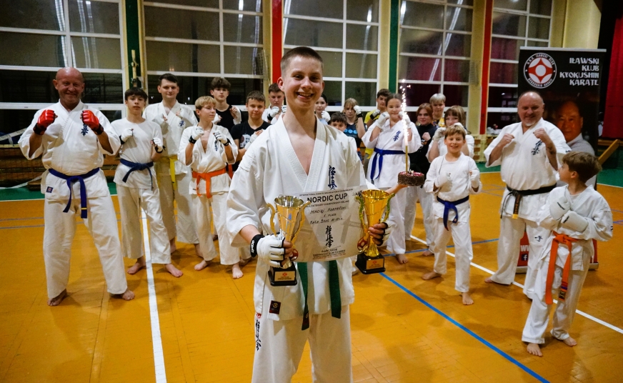 Maciej Korpalski z pucharami wywalczonymi w Finlandii podczas Nordic Cup, a z tyłu - część sportowej rodziny Iławskiego Klubu Kyokushin Karate