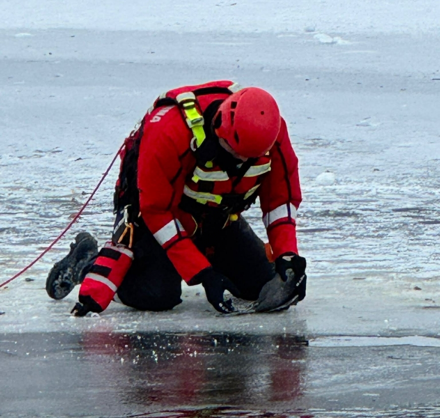 Sekc. Daniel Adamek z KP PSP Iława wyswobadza przymarznietą do lodu łyskę